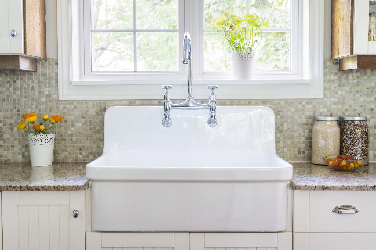 Kitchen interior with large rustic white porcelain sink and granite stone countertop under sunny window