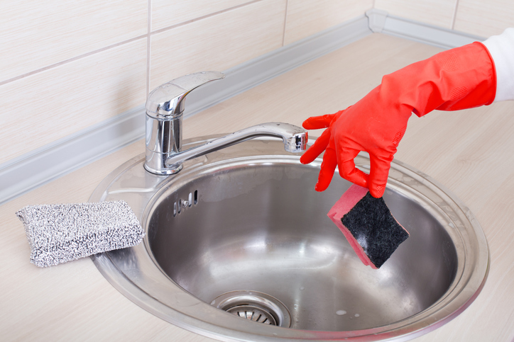 Hand with sponge above kitchen sink