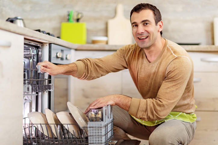 Smiling man using dishwasher.