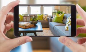 Female holding a smart phone displaying photo of house interior living room